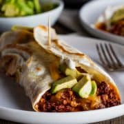a plate of breakfast burritos topped with avocado