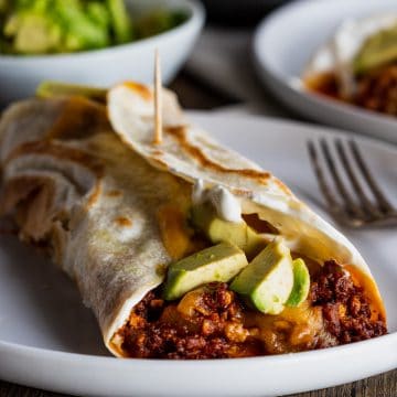 a plate of breakfast burritos topped with avocado